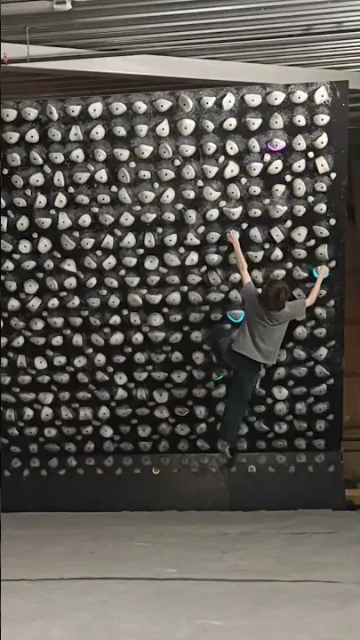 Oliver climbing a Kilter Board wall